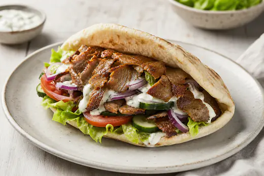Kebabliha pitaleivässä salaatin, tomaatin ja kebabkastikkeen kanssa lautasella