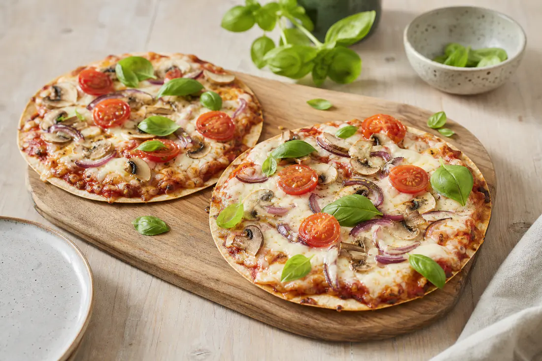 Kaksi pientä rapeaa tortillapizzaa sulaneella mozzarellalla, tomaatilla ja sienillä